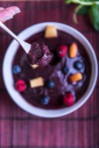 Acai Bowl - a bowl over a desk, full of a intense purple frozen acai