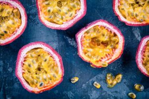 Passion Fruit - 6 fruits with a magenta skin and a yellow pulp full of black seeds.