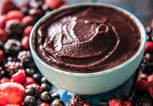 Buy frozen Açaí in bulk - acai bowl over a table full of acai berries