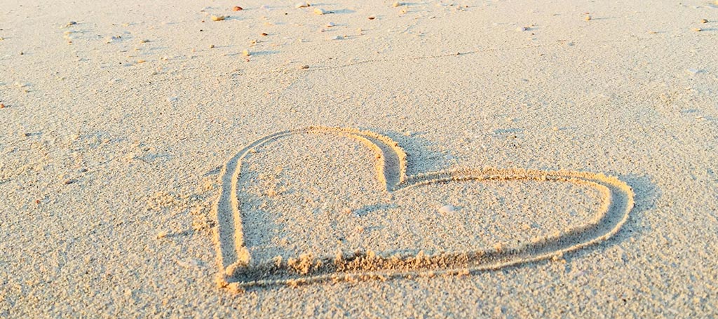 heart drawn in the sand of a beach