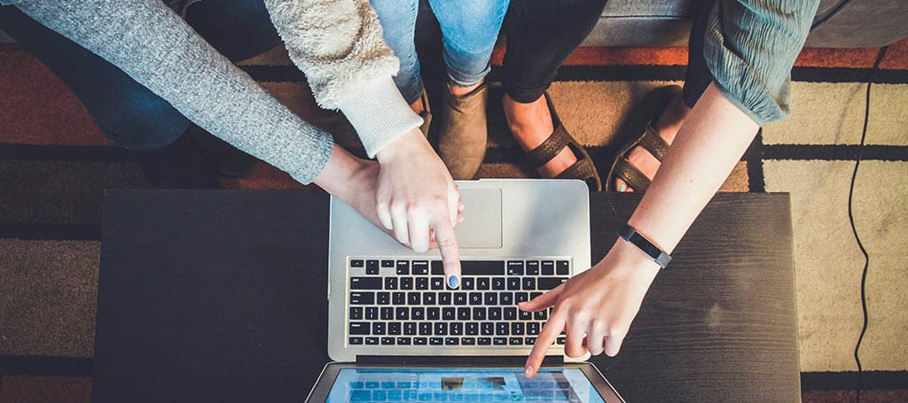 women pointing at a figure on a laptop screen