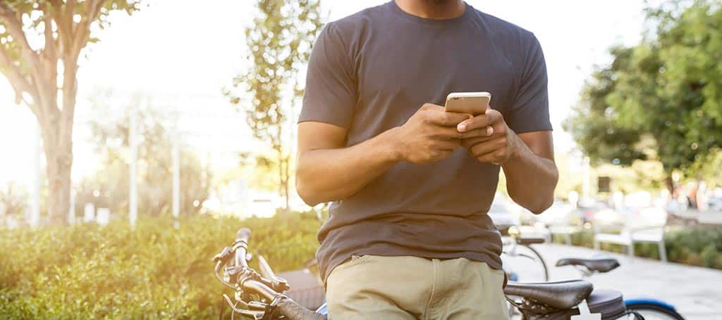 Man leaning on his bike looking at a promotion on his smartphone