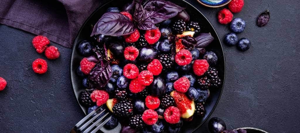 An elegant black plate with red fruits and red leaves