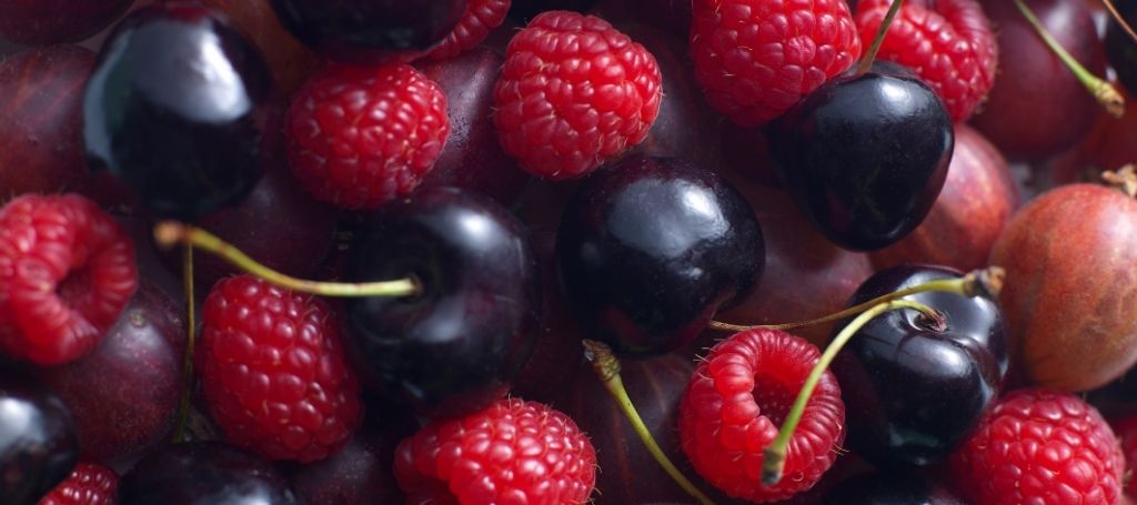 Close up of red fruits: raspberries, cherries, and plums